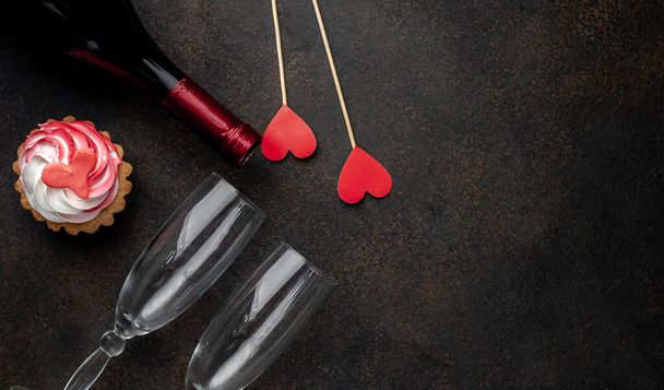 bottle of wine, glasses and cake with drawings in the form of a heart, a gift on a stone background for Valentine's day - Photo, Image