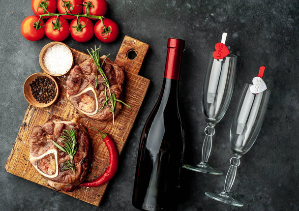 два смажені стейки, з помідорами та спеціями з пляшкою вина та келихами на кам'яному фоні
 - Фото, зображення