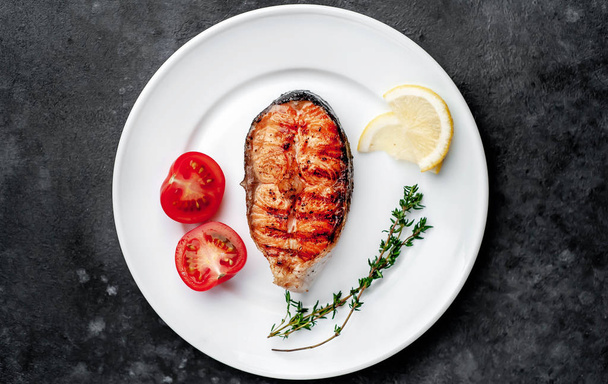 Grilled salmon steak in a white plate with spices on a stone background - Fotoğraf, Görsel