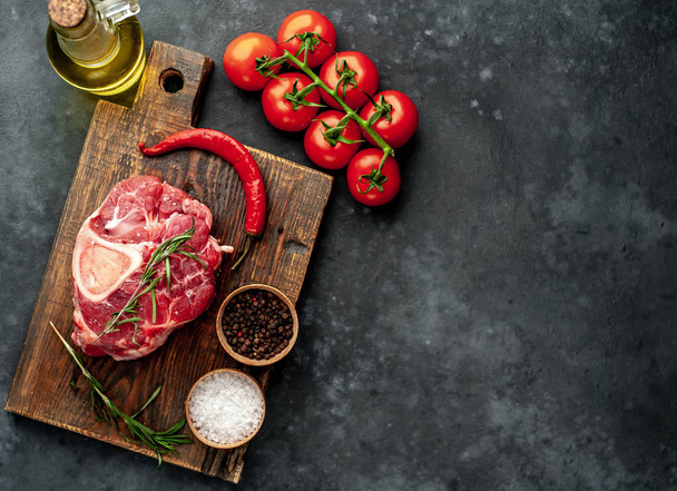 raw beef steak with tomatoes and spices on a stone background. - Fotoğraf, Görsel