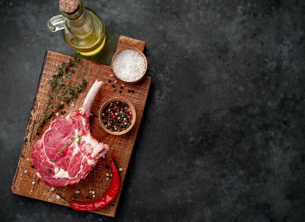 raw beef steak, beef tomahawk with spices, thyme on a stone background. - Fotoğraf, Görsel