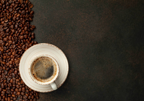 Top view of cup of tasty coffee and beans on a stone background with space for text  - 写真・画像