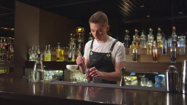 Barman stopt bessen met tang in glas met alcohol in de bar - Video