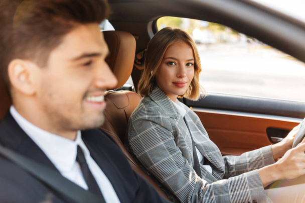 Image of young caucasian businesslike man and woman riding in ca - Photo, Image