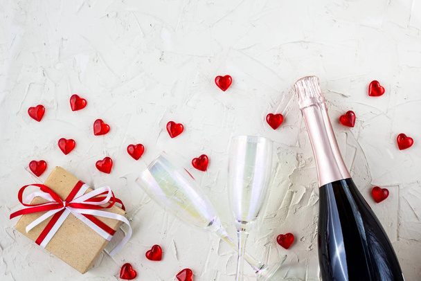 Листівка Валентина з келихами шампанського та пляшкою, серцем та подарунком на білому тлі
 - Фото, зображення