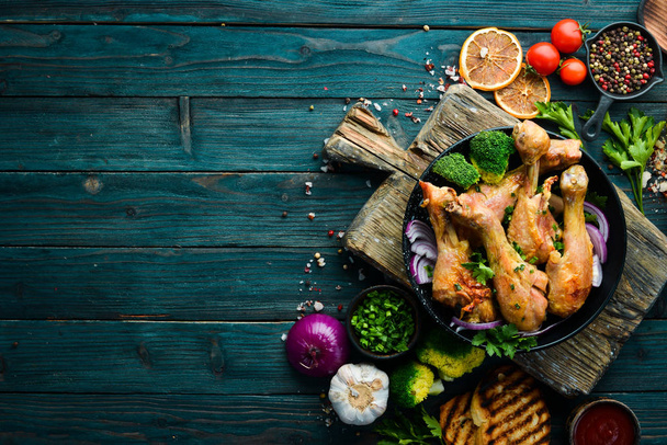 Gebakken kippendrumsticks met groenten op een zwart bord. Kippenvlees. Bovenaanzicht. Vrije ruimte voor uw tekst. - Foto, afbeelding