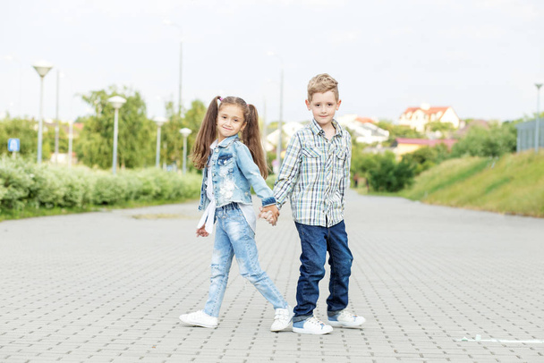 Los niños caminan tomados de la mano. El concepto de la infancia, de vuelta a s
 - Foto, imagen