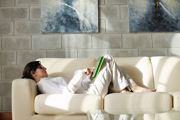 Young woman at home relaxing in her lliving room reading a digital tablet PC surf internet and work - Foto, afbeelding