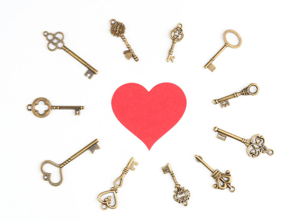 Bronze vintage keys around a red heart icon isolated on white - Fotó, kép
