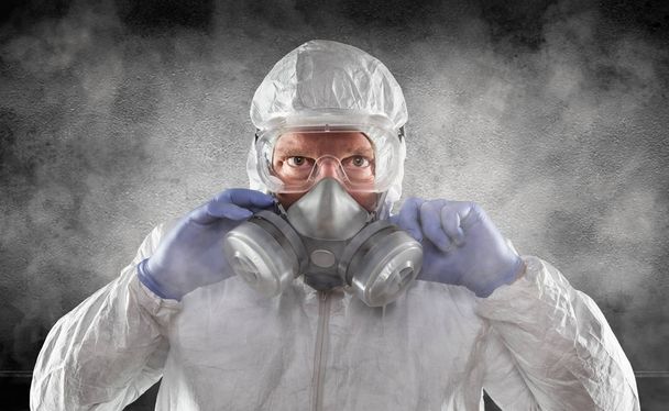 Ο άνθρωπος που φοράει στολή, γυαλιά και μάσκα αερίου είναι καπνιστής σκοτεινό δωμάτιο - Φωτογραφία, εικόνα