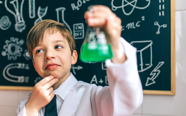 Rapaz atencioso vestido de químico com frasco
 - Foto, Imagem