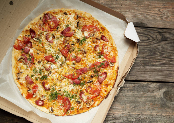 baked round pizza with smoked sausages, mushrooms, tomatoes - Foto, Bild