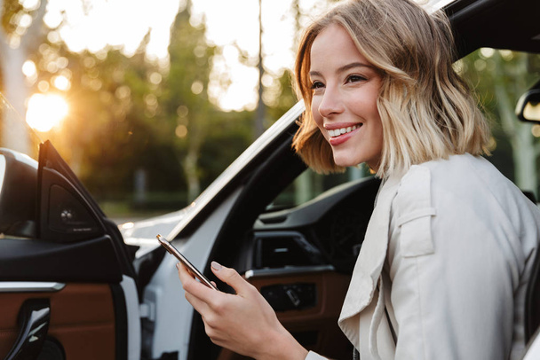 Image of beautiful businesslike woman sitting in car and using c - Photo, image
