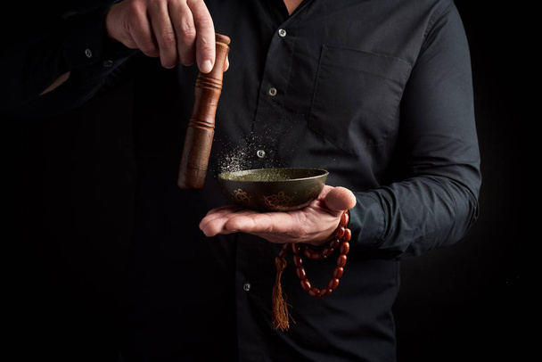 дорослий чоловік в чорній сорочці обертає дерев'яну паличку навколо копа
 - Фото, зображення