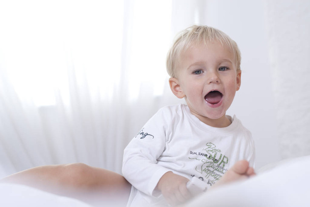 toddler sitting in bed and having fun at home - Фото, изображение