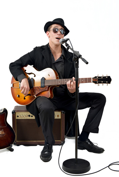 kitaristi laulaa istuen vahvistimen päällä
 - Valokuva, kuva