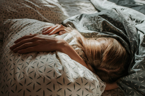 Woman sleep in bed. Blond hair girl under blanket on pillow. Wake up. Dreaming. Happy morning in bedroom. Cozy and comfortable. Sunlight on bed linen. Pillow, blanket. Recovery, relax, lifestyle - Photo, Image