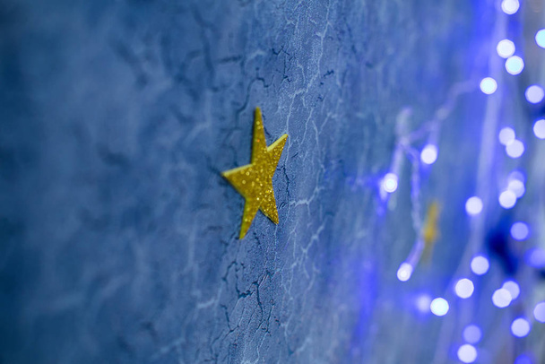 Рождественский глубокий синий потрескавшийся фон с голубыми бликами и гирляндой, размытый фон
 - Фото, изображение