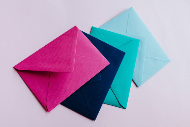 Colored paper envelopes on a light background. New mail, write message. Send and receive letter. Postal delivery service. Blank envelope, empty space. People communication, paperwork. Envelope closeup - Foto, afbeelding
