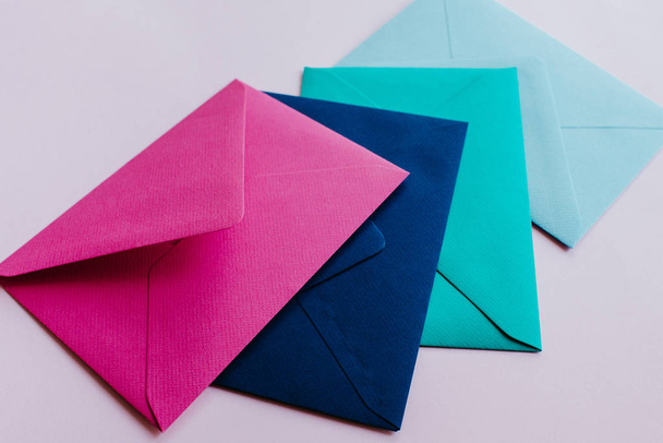 Colored paper envelopes on a light background. New mail, write message. Send and receive letter. Postal delivery service. Blank envelope, empty space. People communication, paperwork. Envelope closeup - Φωτογραφία, εικόνα