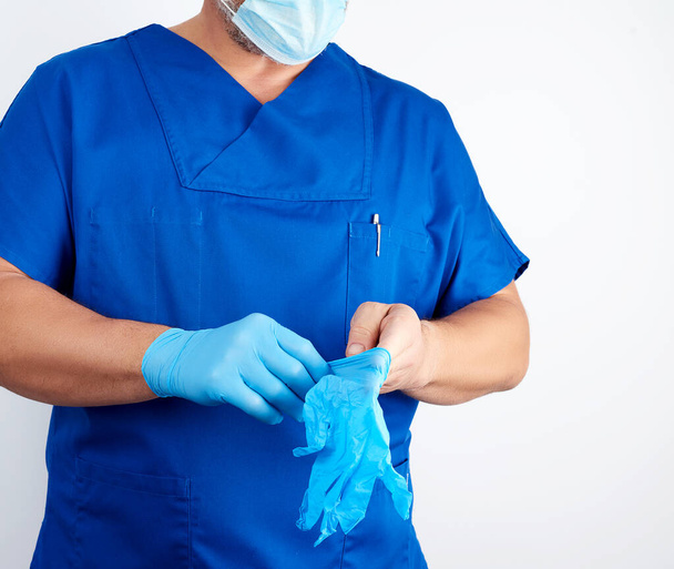 erwachsene männliche Arzt in blauer Uniform legt seine Hände blau steril - Foto, Bild