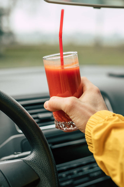 Man driver holding tomato juice in a car - Fotoğraf, Görsel