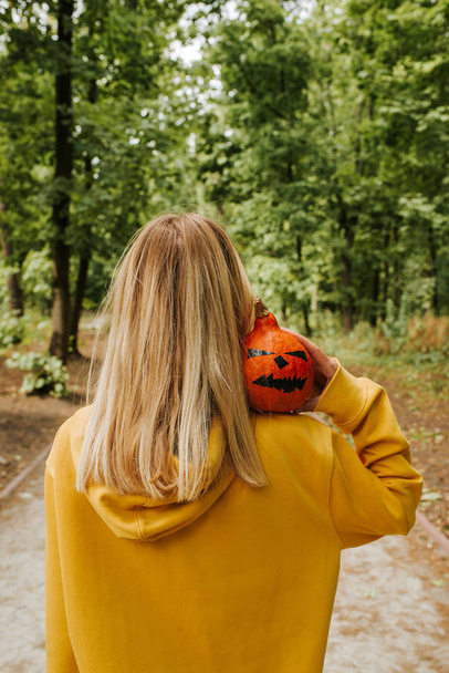 Halloween pumpkin. Woman holding a scary face pumpkin. Happy Halloween party holiday. Celebrate annual in October 31. Autumn season. Fall color, orange and yellow. Trick or treat. Young girl outdoors - Photo, image