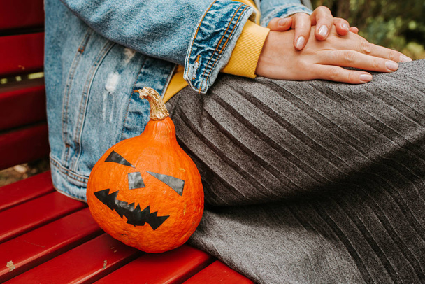 Halloween pumpkin. Woman holding a scary face pumpkin. Happy Halloween party holiday. Celebrate annual in October 31. Autumn season. Fall color, orange and yellow. Trick or treat. Young girl outdoors - Foto, Imagem