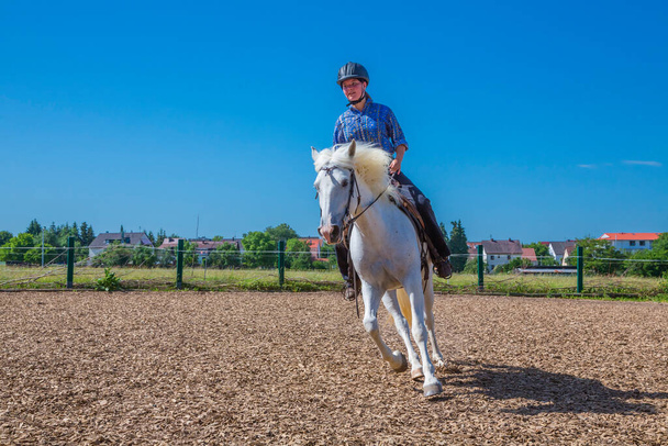 young woman with helmet rides on a riding arena - Foto, afbeelding
