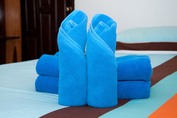 bułka niebieski ręcznik kładzie się na łóżku. - Zdjęcie, obraz