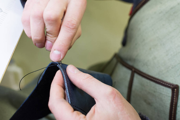 close - up tailor sews leather, leather production, hand seamstress, hand tailor - Zdjęcie, obraz