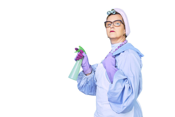 Retrato de velha mulher de limpeza em avental com escova de limpeza de poeira isolada em fundo azul. equipamento especial uniforme e profissional para limpeza
 - Foto, Imagem