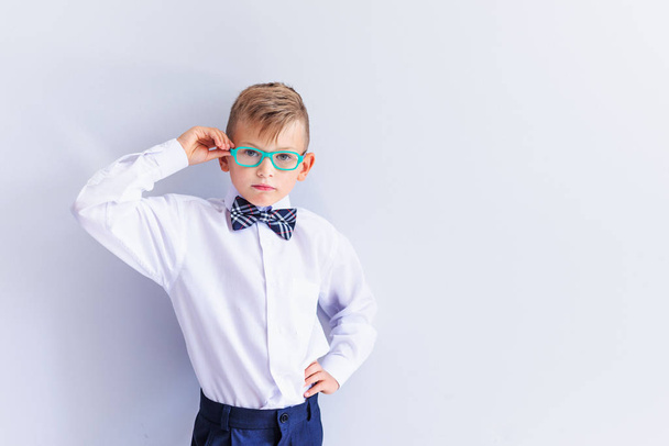 A small cheerful, cute, fashionable blond boy with glasses looks at the camera trying on glasses.The concept of health. Vision correction. Ophthalmology. - Foto, Imagen