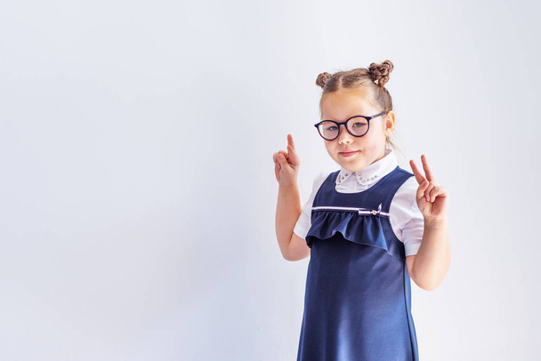 A beautiful little brunette girl looks at the camera trying on glasses. Vision correction. Ophthalmology. - Foto, afbeelding
