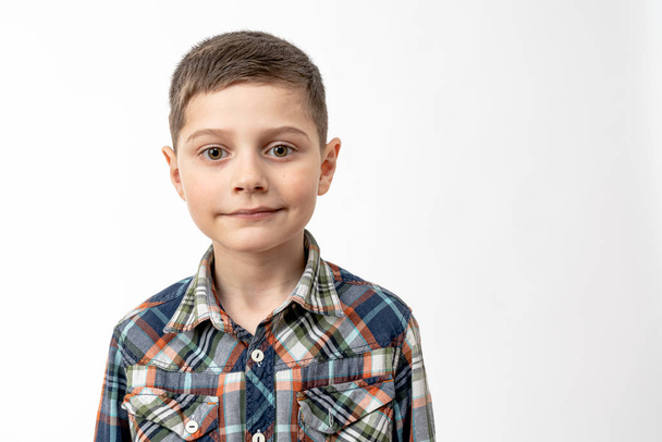 Close-up portret van de zelfverzekerde knappe kleine jongen in shirt dat kijken naar de camera geïsoleerd over witte achtergrond, copyspace voor uw tekst - Foto, afbeelding