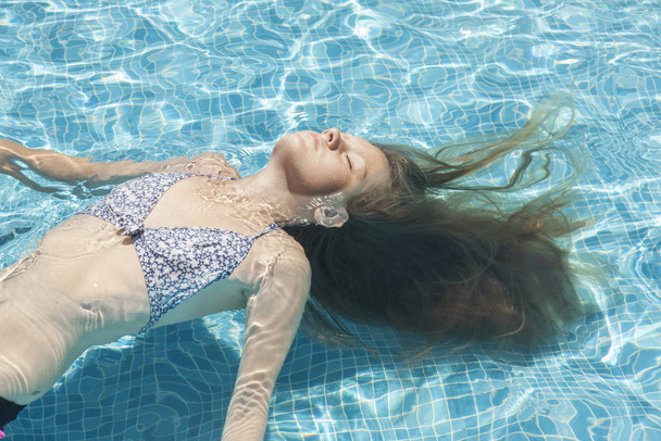 Teenager relaxing in a pool in the summertime - Photo, image