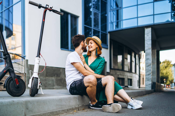 Young loving couple relaxing sitting near a modern glass buildin - Фото, изображение