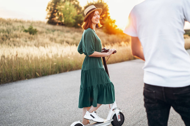 Happy couple walking on scooters. A young woman in dress and hat - Foto, Bild
