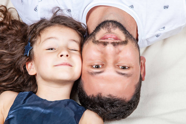 Vater und Tochter liegen Kopf an Kopf auf dem Bett - Foto, Bild