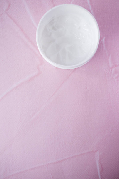 Crème voor de huid in de pot, huidverzorgingsproduct. Bovenaanzicht op roze achtergrond. plaats voor tekst. - Foto, afbeelding