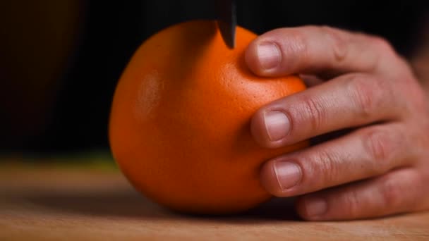 Oranje vers. Recept. Mes in de hand snijdt sappige sinaasappel op een snijplank. - Video