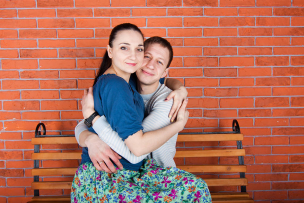 Una pareja joven se abraza y se sienta en el banco. Fotografía de interior
 - Foto, Imagen