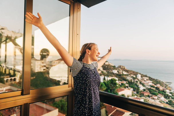 Giovane ragazza che ammira un bellissimo paesaggio dal balcone, braccia aperte, vacanze estive al mare, viaggi in famiglia con bambini
 - Foto, immagini