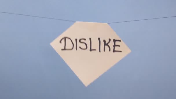 Un hombre cuelga una hoja blanca de papel con una inscripción negra que no le gusta sobre un fondo azul
 - Metraje, vídeo