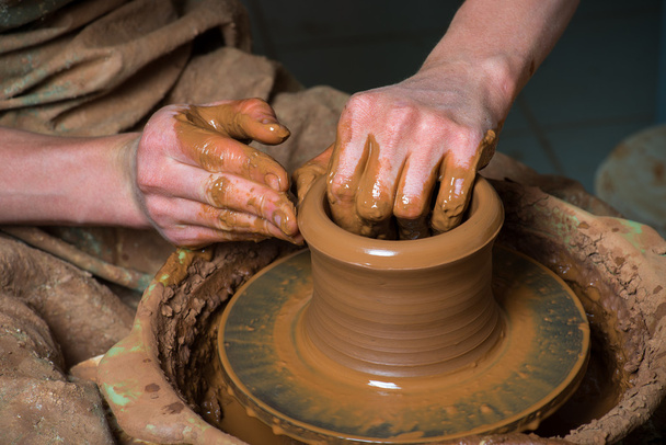hands of a potter, creating an earthen jar on the circle - Photo, Image