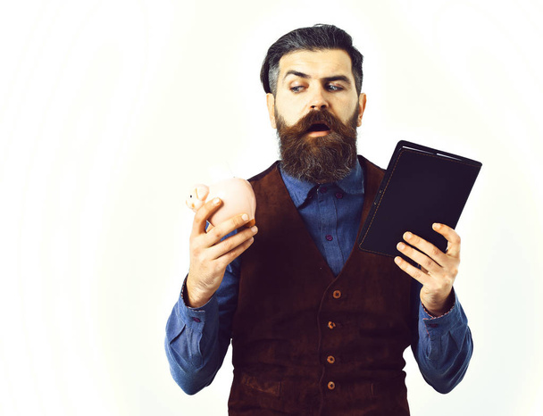 bearded man holding notepad and moneybox with serious face - Fotó, kép