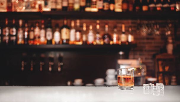 Vaso de whisky con soportes de hielo en barra de bar, fondo marrón oscuro
 - Foto, Imagen