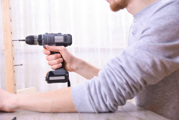 Man is working with furniture assembly using electric screwdriver in new house installation - technician onsite work using hand tools concept - 写真・画像