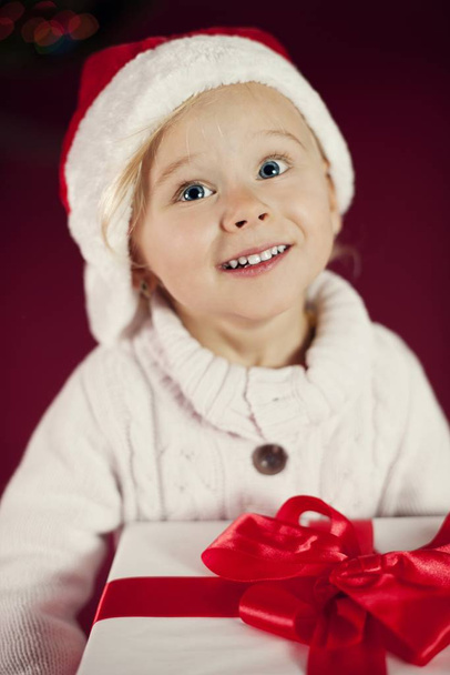 Cute girl with santa hat holding christmas gift  - Photo, image