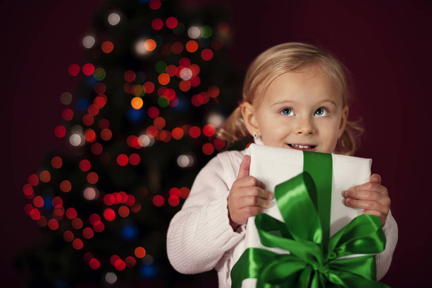 Little girl holding christmas gift - Фото, изображение
